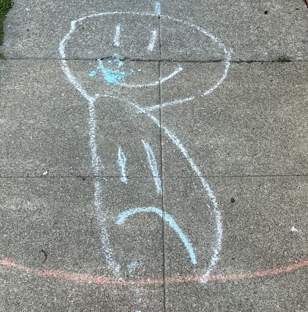 a smiley face and a frowning face drawn side by side on the sidewalk with chalk